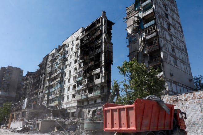 Pekerja Kementerian Situasi Darurat Republik Rakyat Donetsk membersihkan puing-puing di samping bangunan yang rusak akibat pertempuran sengit di Mariupol, di wilayah di bawah pemerintahan Republik Rakyat Donetsk, Ukraina timur, Kamis, 12 Mei 2022.