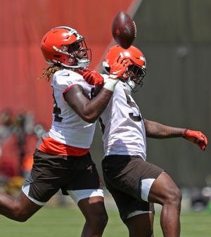 Browns defensive end Alex Wright, left, punches the ball away from defensive end Isaiah Thomas, right, during rookie minicamp in Berea on Friday.