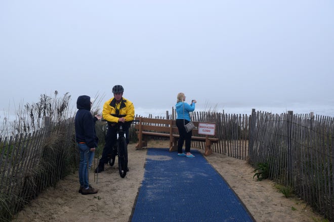 A police officer speaks to citizens atop a dune at Garfield Parkway in Bethany Beach. All dune crossings in Bethany Beach were closed May 13.