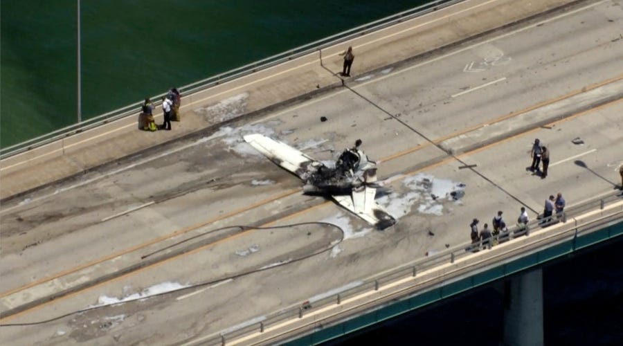 This photo provided by WSVN-TV emergency personnel respond to a small plane crash in Miami on Saturday, May 14, 2022. The small plane has crashed on a bridge near Miami, striking an SUV and bursting into flames. The Federal Aviation Administration reported the single-engine Cessna 172 lost power just before Saturday's crash.