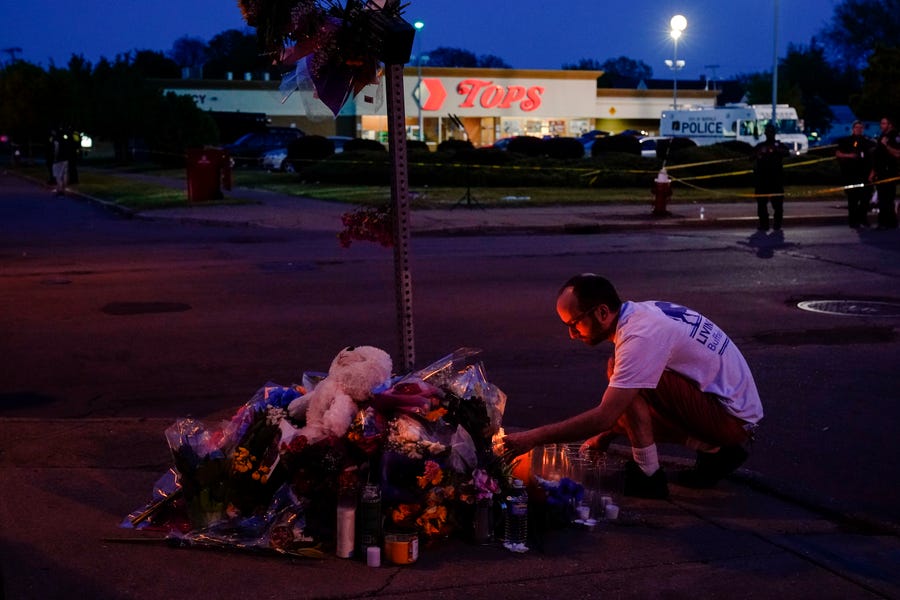 A person pays his respects outside the scene of a shooting at a supermarket, in Buffalo, N.Y., Sunday, May 15, 2022.