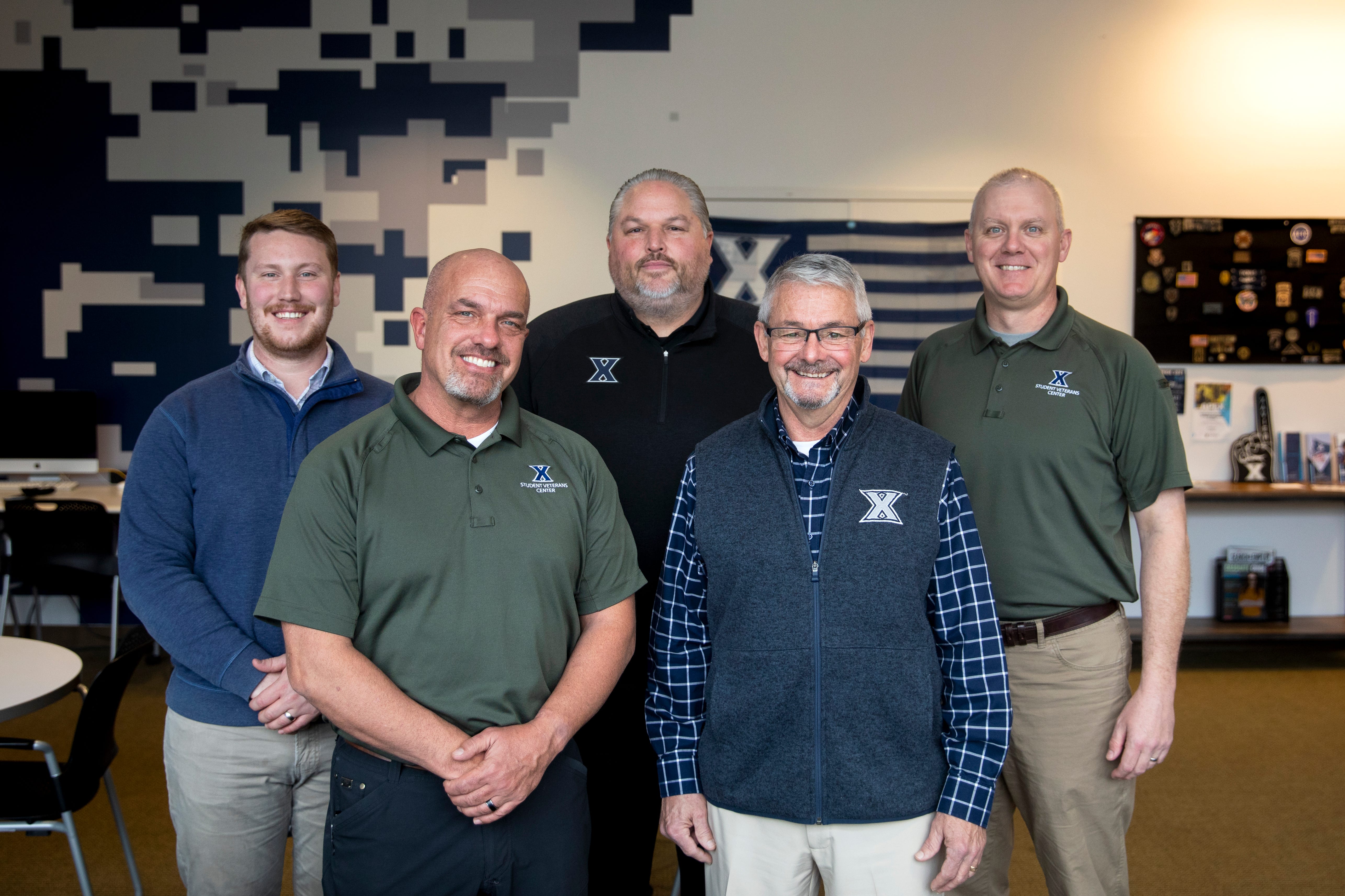 Xavier University's Student Veterans Center's Nathan Ray, assistant director of veterans admissions, Paul Fellinger, Jr., director, Matt Jennings, assistant athletic director for strength and conditioning, Glenn Welling, Jr., senior advisor, and Jason Nahrgang, assistant director of career and external relations, stand for a portrait inside the Student Veterans Center at Xavier University on Dec. 10, 2022. Jennings and members of the Student Veterans Center have undertaken a project to rename the Center after Xavier alumnus, Capt. Phil Bucklew. The plan is for the dedication to be completed on June 6, 2024, the 80th anniversary of D-Day.