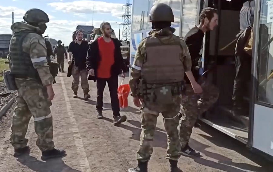 In this photo taken from video released by the Russian Defense Ministry Press Service on Tuesday, May 17, 2022, Russian servicemen watch Ukrainian servicemen boarding a bus as they are being evacuated from the besieged Azovstal steel plant in Mariupol, Ukraine. More than 260 fighters, some severely wounded, were pulled from a steel plant on Monday that is the last redoubt of Ukrainian fighters in the city and transported to two towns controlled by separatists, officials on both sides said.   (Russian Defense Ministry Press Service via AP) ORG XMIT: XDL109