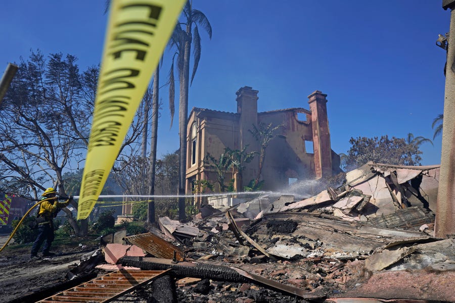 A firefighter hoses down hot spots from a home in the aftermath of the Coastal Fire Thursday, May 12, 2022, in Laguna Niguel, California.