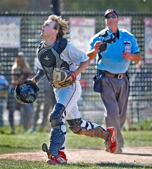 Hingham High senior catcher Ben Cashman runs after a foul ball under the watch of umpire Mark Igo during a home game against Marshfield on Wednesday, May 18, 2022.