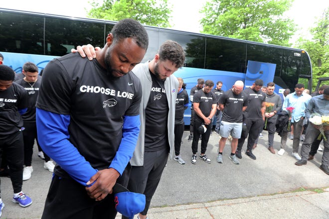 Buffalo Bills running back Taiwan Jones and Quarterback Josh Allen pray with their teammates near the site of the last Saturday's mass shooting at the Tops supermarket in Buffalo, N.Y. May 18, 2022. Members or the team visited the site and then helped distribute food to members of the community.