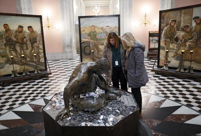 Ohio House of Representatives employees Kristin Harris, right, and Kim Hartman stop to look at the bronze statue titled "Silent Battle" in the middle of The Eyes of Freedom: Lima Company Memorial at the Ohio Statehouse rotunda in Columbus on Friday, Jan. 31, 2020.