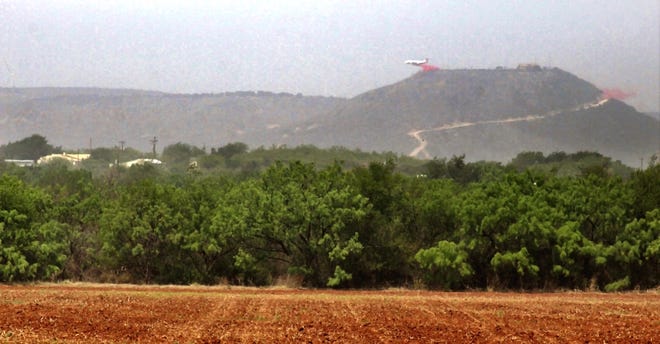 Haze filled the area Thursday near View and U.S. Highway 277 because of the Mesquite Heat Fire. An aircraft tanker in the distance drops flame retardant on a hilltop.