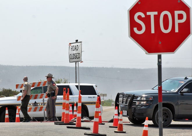 A Taylor County Sheriff's Office deputy and a Department of Public Safety trooper man a roadblock at U.S. Highway 277 and FM 1235 on Thursday. Other roads going south were blocked to regular traffic.