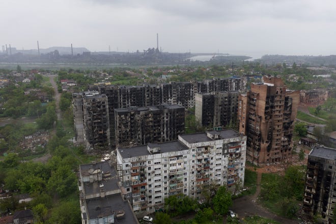 .Pemandangan udara dari bangunan tempat tinggal yang rusak dan pabrik baja Azovstal di latar belakang di kota pelabuhan Mariupol pada 18 Mei 2022, di tengah aksi militer Rusia yang sedang berlangsung di Ukraina..