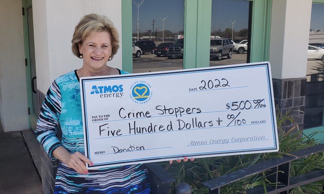 Jackie Riley, board member of Crimestoppers of Wichita Falls holds a donation check from Atmos Energy.