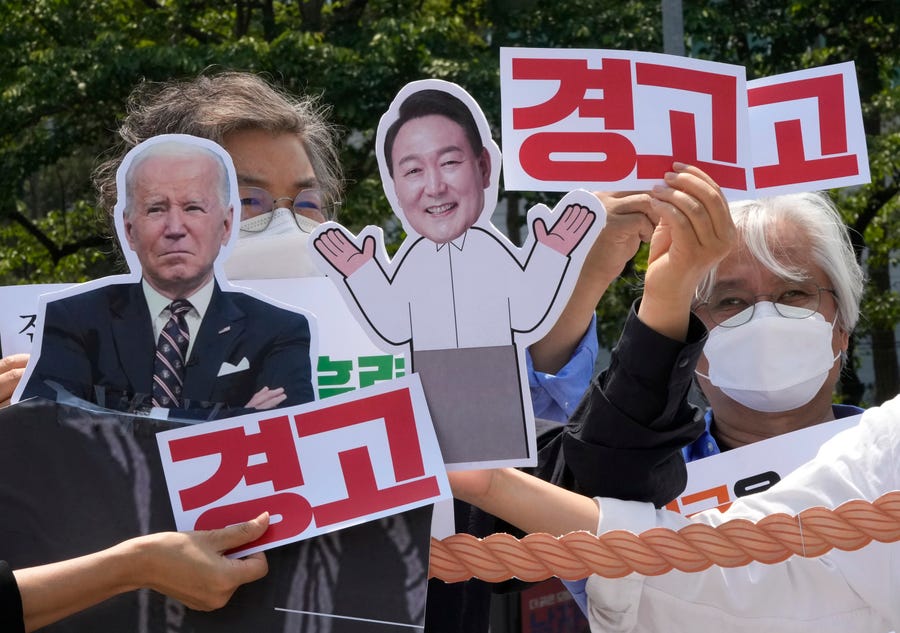 Protesters with images of U.S. President Joe Biden, left, and South Korean President Yoon Suk Yeol stage a rally to denounce policies of the United States on North Korea near the presidential office in Seoul, South Korea, Tuesday, May 17, 2022.