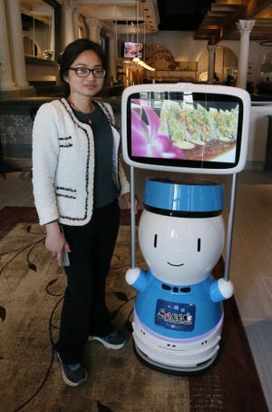 Co-owner Tiffany Chen stands next to the host robot at the new restaurant Sake Japanese Fusion at Summit Mall in Fairlawn.