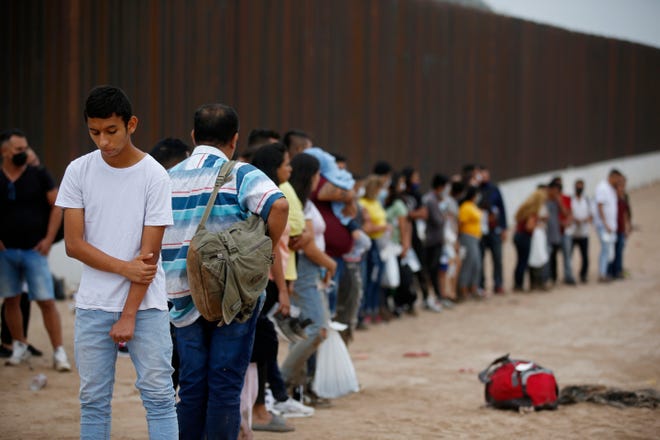 Para migran yang telah menyeberangi sungai Rio Grande menuju AS menunggu untuk diproses oleh agen Patroli Perbatasan AS di Eagle Pass, Texas, Jumat, 20 Mei 2022.