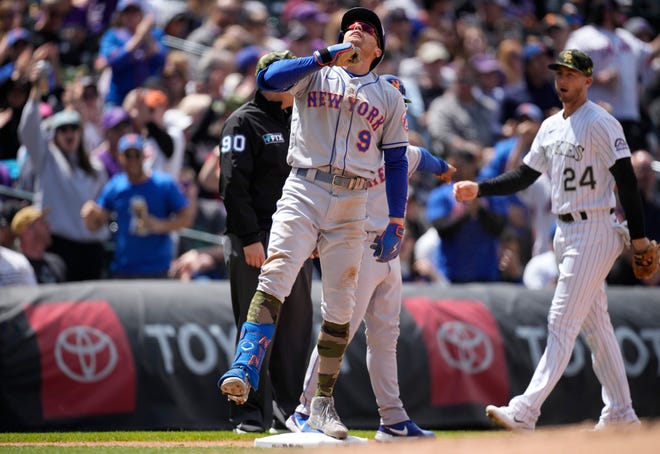 New York Mets' Brandon Nimmo, front, reacts after reaching third base on a single and a throwing error by Colorado Rockies right fielder Randal Grichuk as third baseman Ryan McMahon looks on in the sixth inning of a baseball game, Sunday, May 22 2022, in Denver.