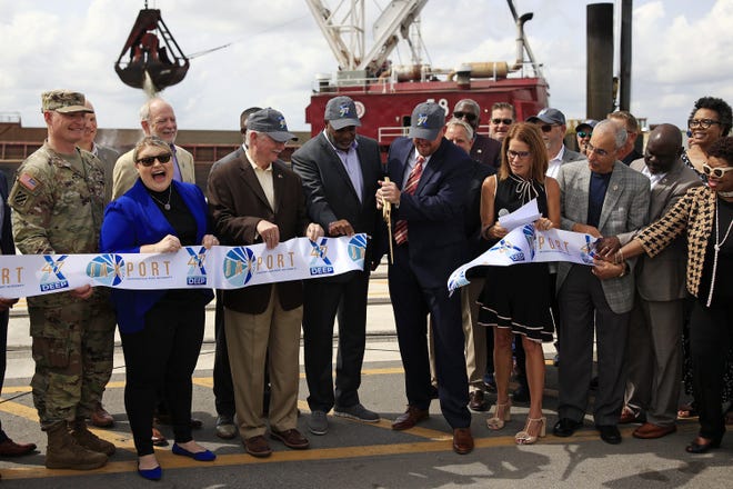 U.S. Rep. Kat Cammack, left in blue, reacts Monday as Florida Department of Transportation Secretary Jared W. Perdue cuts the ribbon next to JaxPort CEO Eric Green for the completion of 11 miles of river deepening. A clamshell behind them dipped into the water for the ceremonial last scoop.