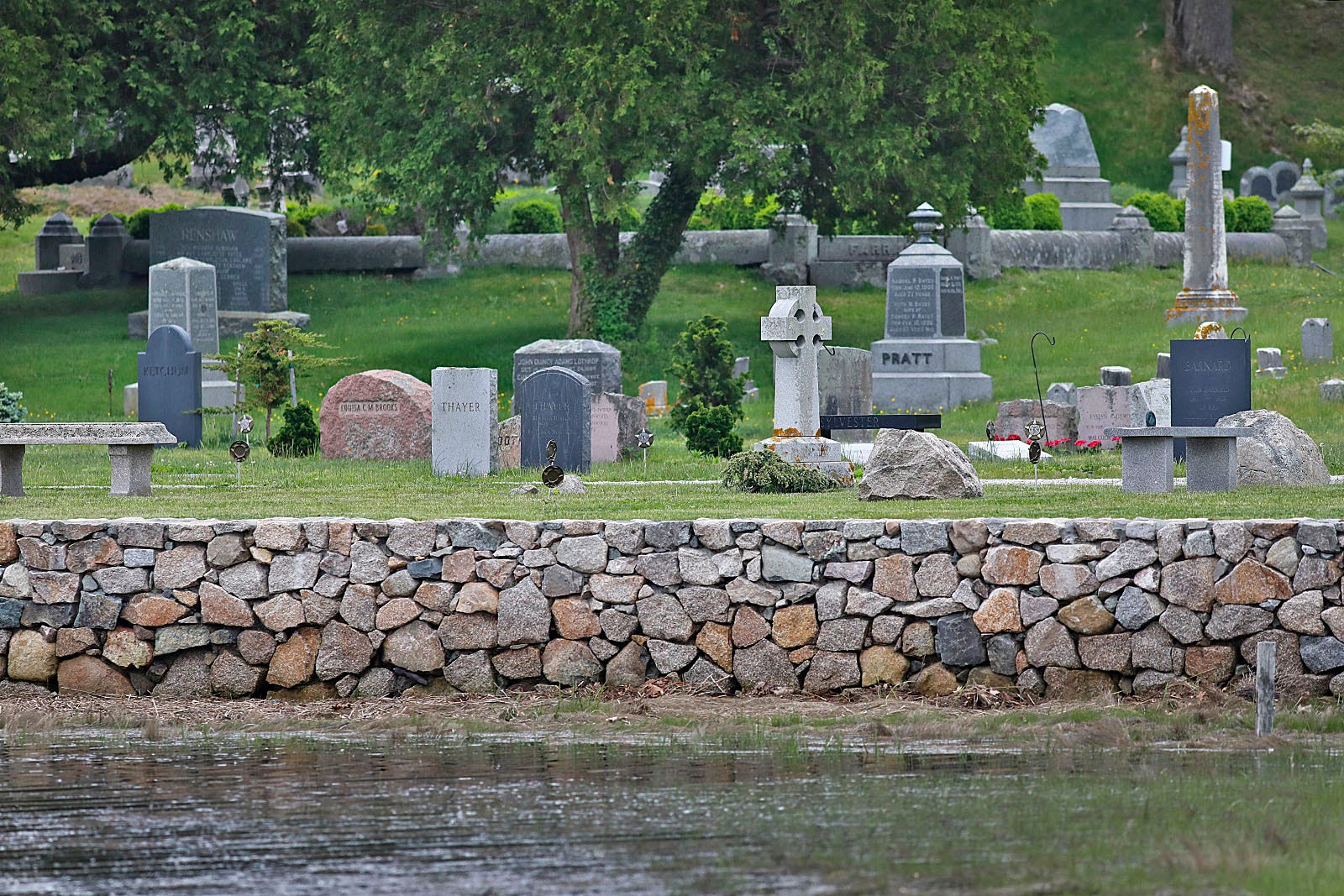 Cohasset Central Cemetery is pictured from the water. Little Harbor, the Atlantic Ocean inlet with which it shares a border, was flooding the cemetery for years. The board of directors undertook a project to build this seawall, which elevated the headstones on top of new ground fill.