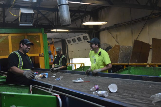 Three Emmet County Recycling employees sort items on a conveyor to be properly recycled. When batteries end up on the conveyor, they can cause injury to employees.
