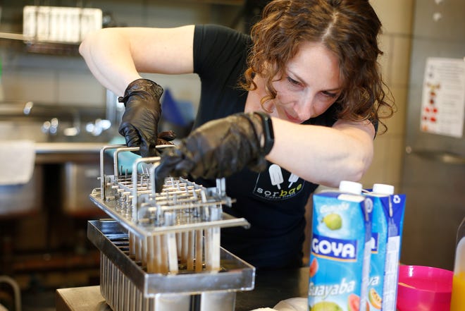 Monica Ferracioli places popsicle sticks into the mold for the passion fruit popsicles she is making at the newly opened Sorbae Frozen Treats at Fort Taber Park in New Bedford.