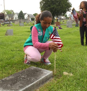 Local Girl Scout Elizabeth Baez places a flag at a veteran's grave in the Beech Grove Cemetery Saturday.