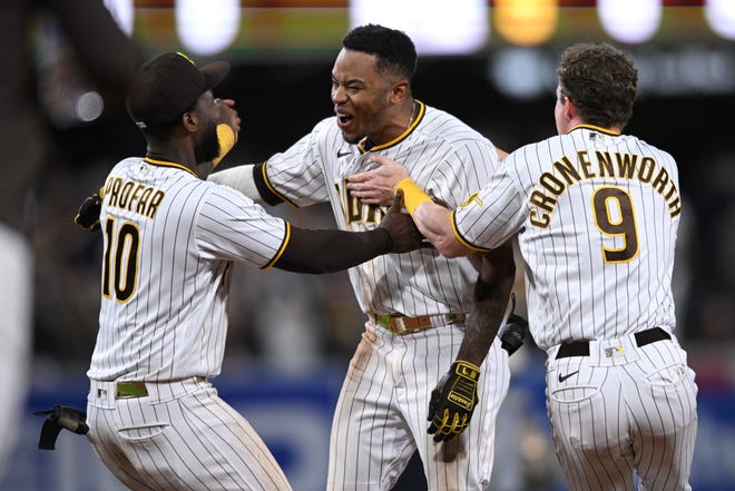 Padres centerfielder Jose Azocar (center) is congratulated by teammates after hitting a walk-off single in the 10th inning against the Brewers on Monday night.