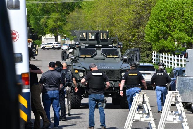 An armored police vehicle and law enforcement officers stand by at a police standoff Tuesday morning in south St. Cloud.