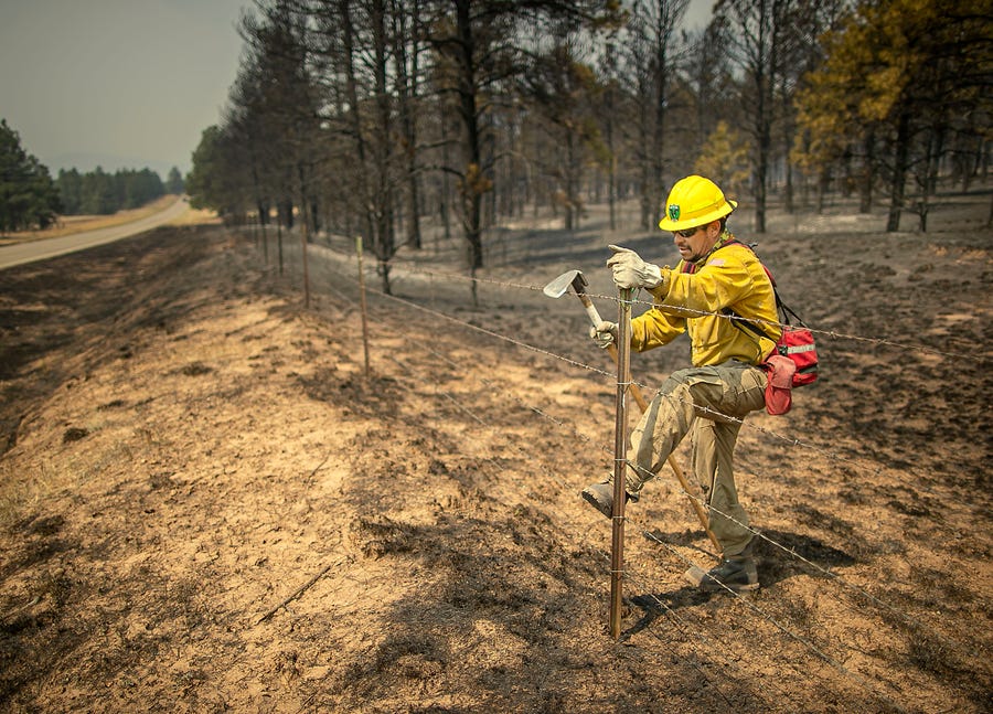 Firefighter Vadix Armendarez looks for hot spots along State Highway 434 north of Mora after a late night on the line as firefighters from all over the country converge on Northern New Mexico to battle the Hermit's Peak and Calf Canyon fires on May 13, 2022.