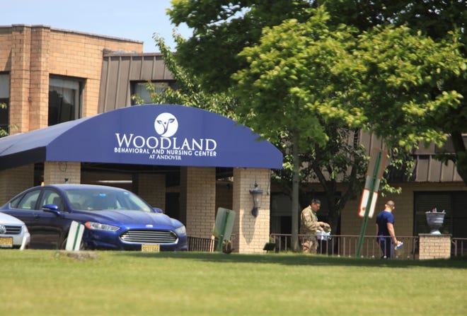 A member of the New Jersey National Guard walks out with an employee of Woodland Behavioral and Nursing Center on Wednesday, May 25, 2022.