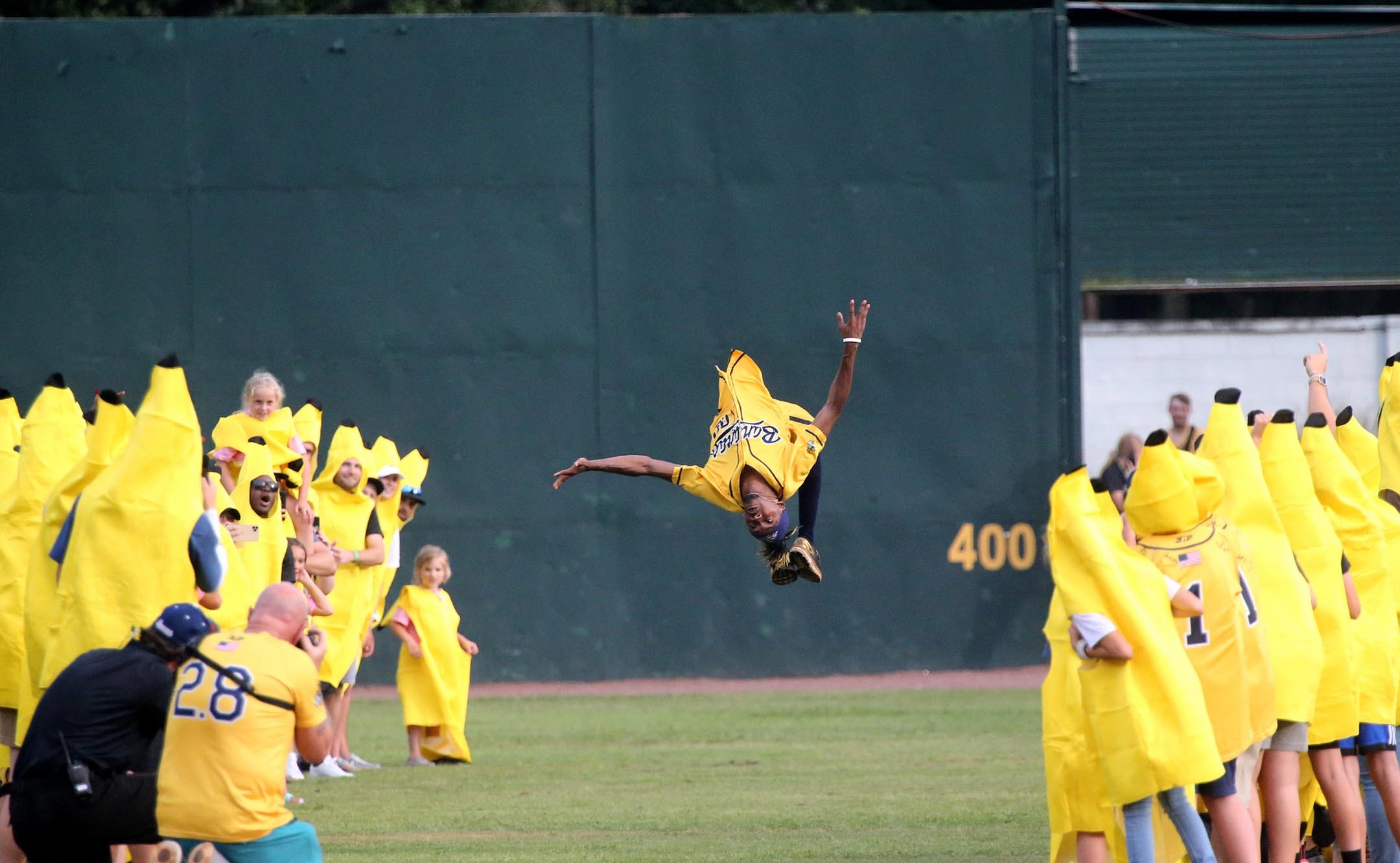 Savannah Bananas dancing first base coach Maceo Harrison flips through a tunnel of fans as he is introduced at Grayson Stadium.