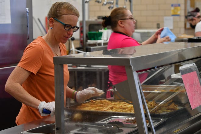 Deidra Roberts prepares lunch for Heaton Middle School students in the cafeteria on May 25.