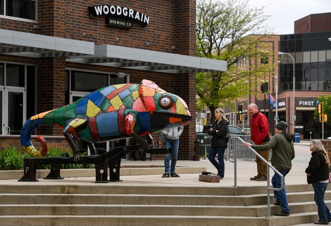 People look at the "Junkyard Chameleon" Sculpture Walk installation downtown on Wednesday, May 25, 2022, in Sioux Falls.
