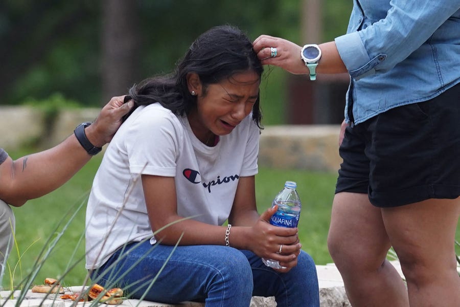 A girl cries, comforted by two adults, outside the Willie de Leon Civic Center where grief counseling will be offered in Uvalde, Texas, on May 24, 2022.