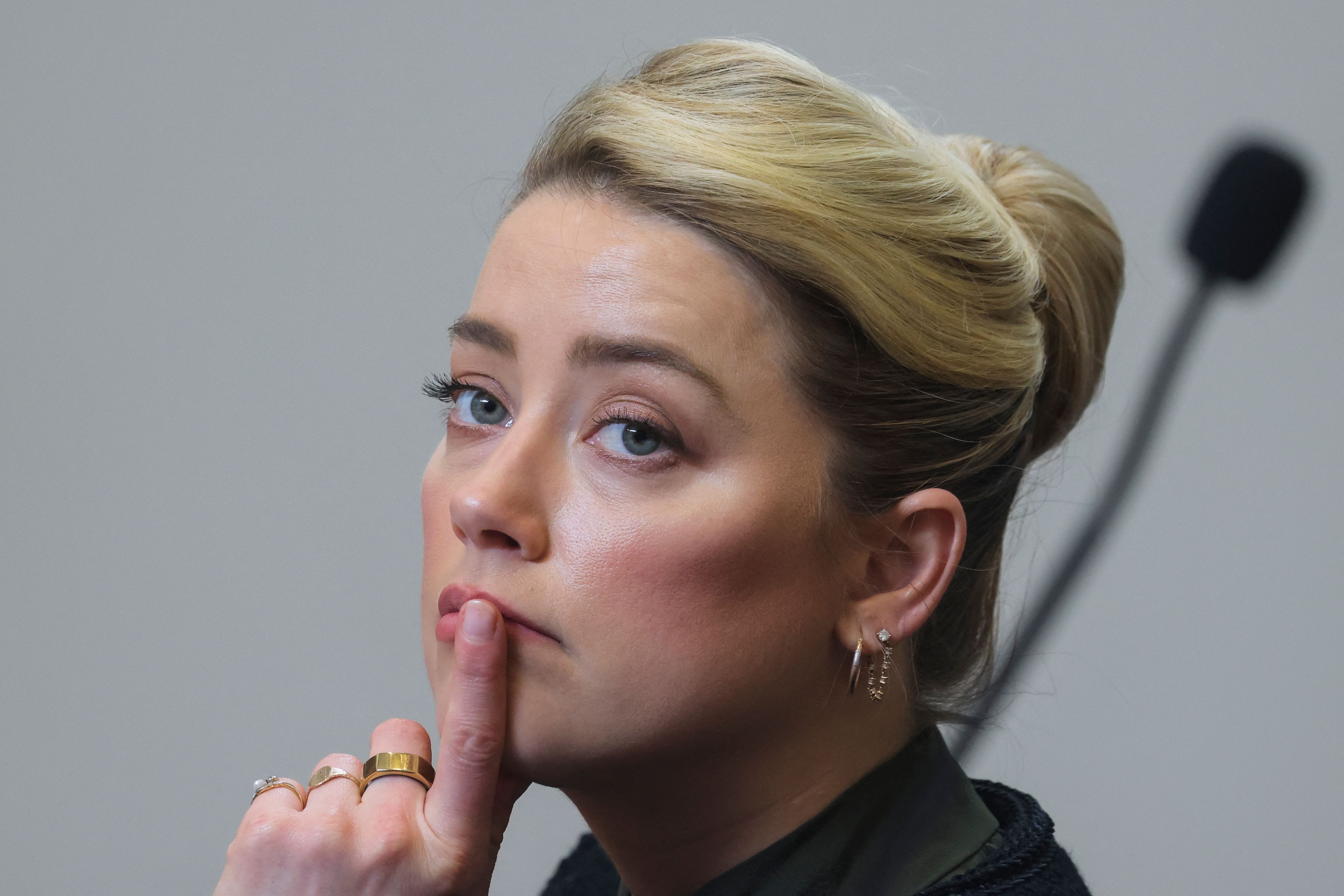 Amber Heard listens to her ex-husband actor Johnny Depp's testimony during his defamation trial against her, at the Fairfax County Circuit Courthouse in Fairfax, Virginia, on May 25, 2022.