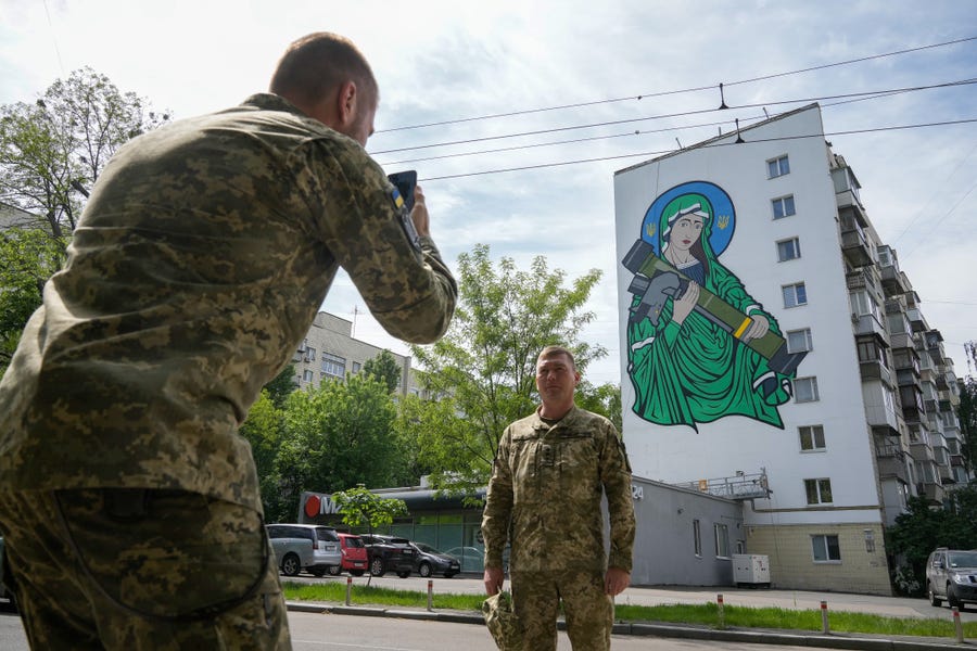 Ukrainian soldiers take pictures of a mural titled 'Saint Javelin' dedicated to the British portable surface-to-air missile has been unveiled on the side of a Kyiv apartment block on May 25, 2022 in Kyiv, Ukraine.