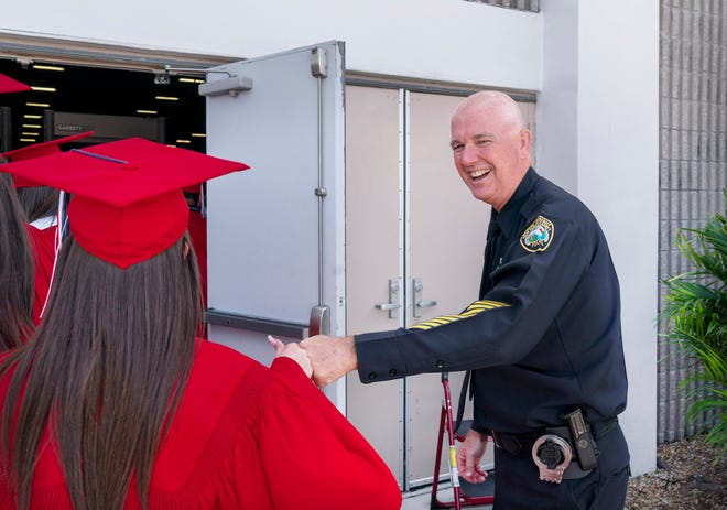 School police officer Andrew Rundle gives the last fist bumps of the year to Forest Hill High School seniors before they graduate at the South Florida Fairgrounds on May 24.