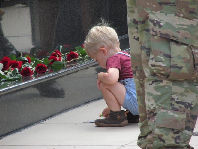 A child crouches near the U.S. Army Special Operations Command's memorial wall during a Gold Star memorial ceremony Thursday, May 26, 2022, at Fort Bragg.