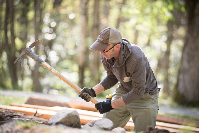 Sean Perry wields a pickax to rebuild a retaining wall at the unique bridge entrance of Palmer Barn during the 2018 restoration project in Cataloochee, Great Smoky Mountains National Park.