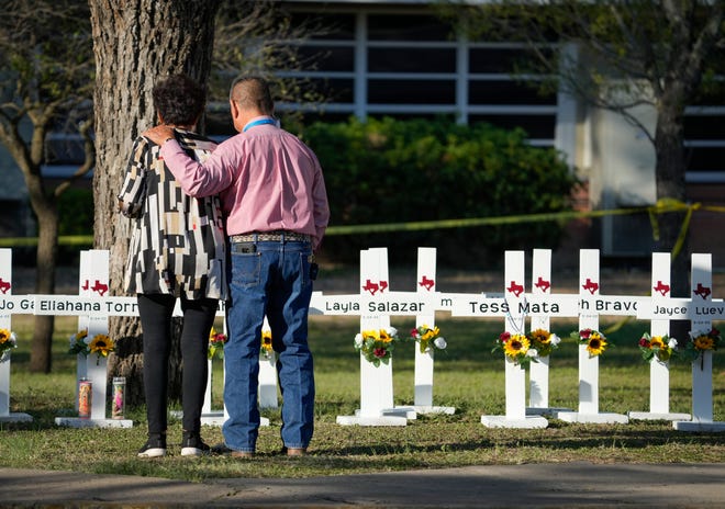 Daniel and Matty Myers of Tabernacle of Worship in Uvalde, Texas, pray May 26 as people pay respects at a memorial near Robb Elementary School, where a gunman shot and killed 19 children and two adults.