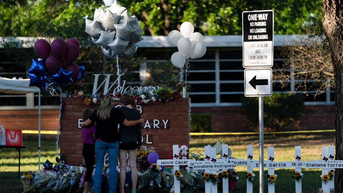 May 26, 2022: A family pays their respects next to crosses bearing the names of Tuesday's shooting victims at Robb Elementary School in Uvalde, Texas.