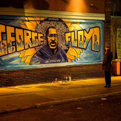 A woman looks at a mural on the wall of Cup Foods 