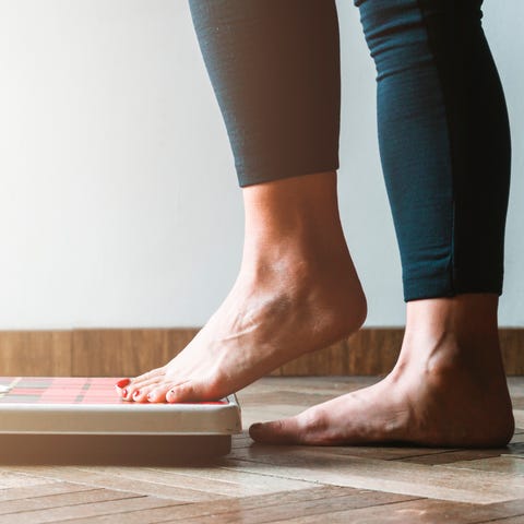 Female checking kilogrammes getting on the scale -