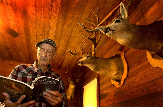 Murry Burnham flips through a photography book by his good friend Erwin Bauer, the preeminent wildlife photographer of his time, while looking through items in his second story loft, which is filled with deer heads and other memorabilia. Burnham died in April.
