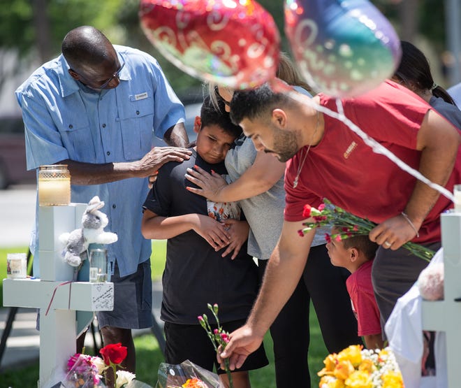 Mourners place flowers, candles and tokens on crosses for each of the Robb Elementary School shooting victims at a memorial put up in the Uvalde Town Square, May 27, 2022. 