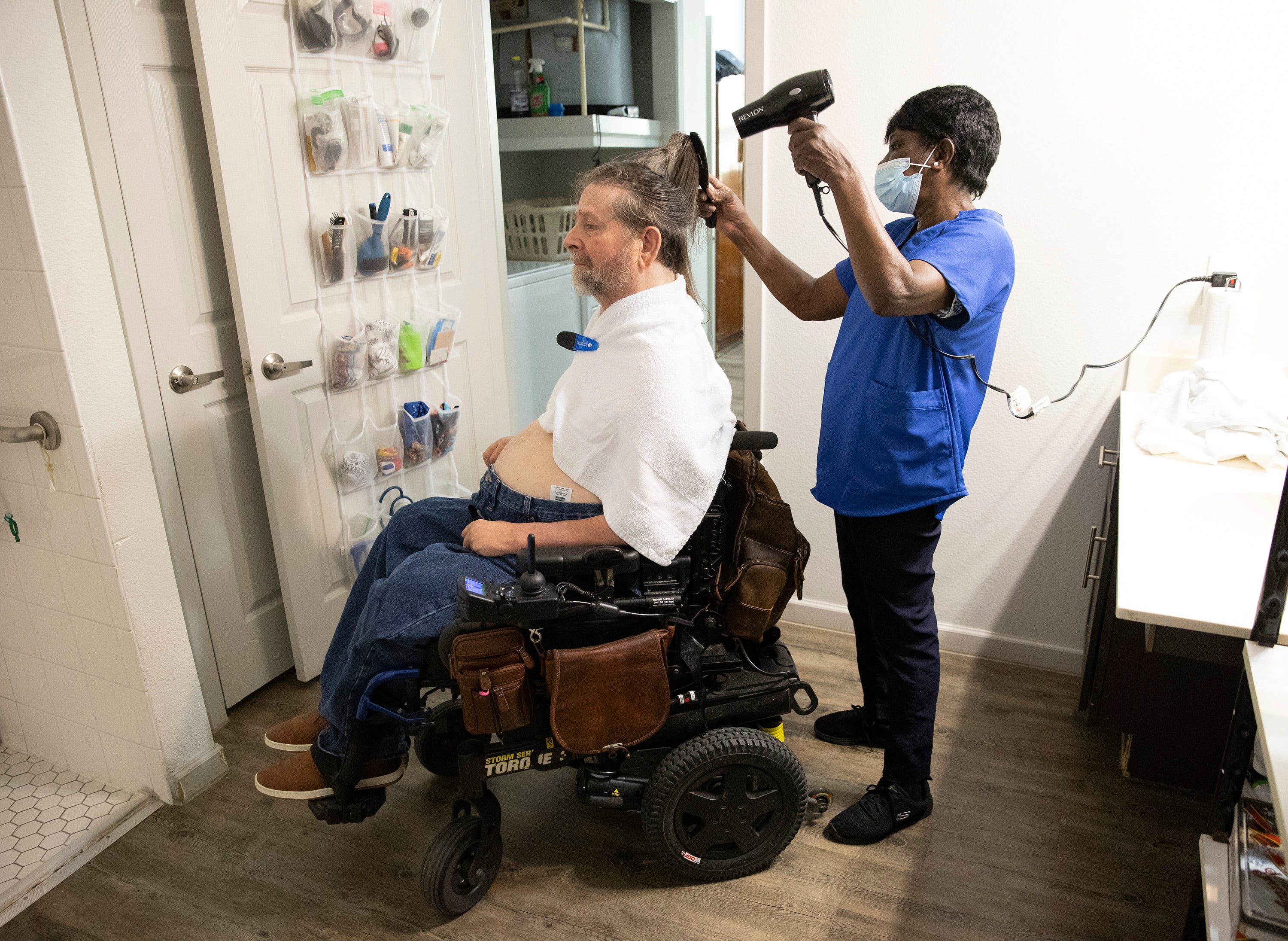 Home health caregiver Shirley Eason dries the hair of Gene Rodgers, a quadriplegic, at his home in Austin in May.