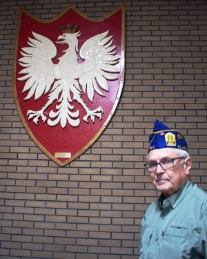 Walter Nosek, commander of the Clinton Polish American Veterans Club, in front of an eagle plaque created by a member.