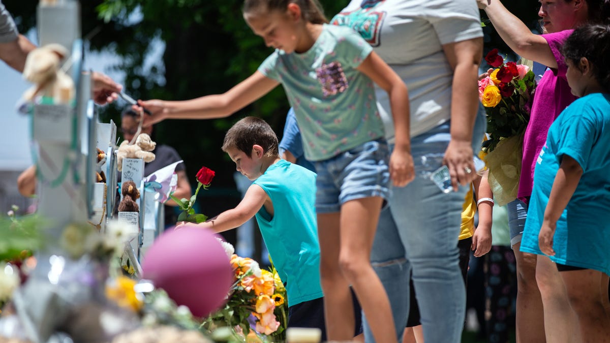 Mourners place flowers, candles and tokens on crosses for each of the Robb Elementary School shooting victims at a memorial put up in the Uvalde Town Square, May 27, 2022.