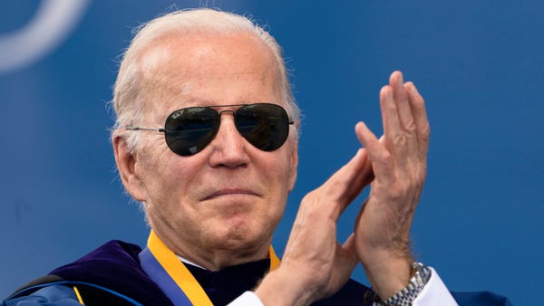 President Joe Biden applauds during the University