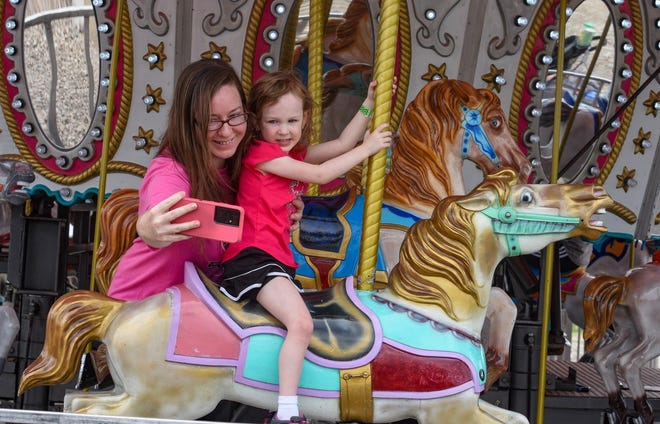 A mom and daughter take a selfie on the carousel.