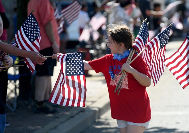 Serenity Reynolds, a Girl Scout with Troop 60377 in Canton, passes out flags along on Tuscarawas Street W during this year's Canton Memorial Day Parade and Ceremony.