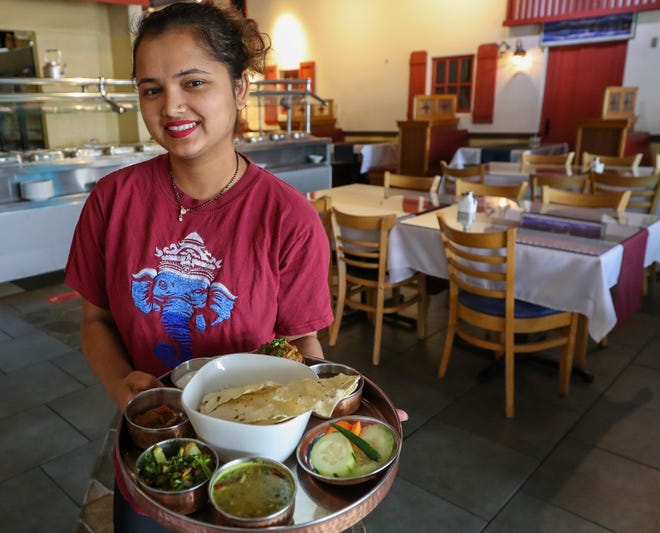 Bhawana Niroula, a server at the Namaste Indo-Nepali Cuisine in the Stonebridge Plaza at Morse and Hamilton roads, holds a Daal-Bhat-Tarkari platter, a traditional Nepali dish made with rice, lentils and curry.